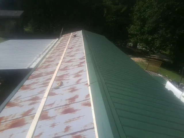 Old rusted panels beside newly installed green metal roofing — Wind Damage Roof Repair by Roofing Brothers in Plain City