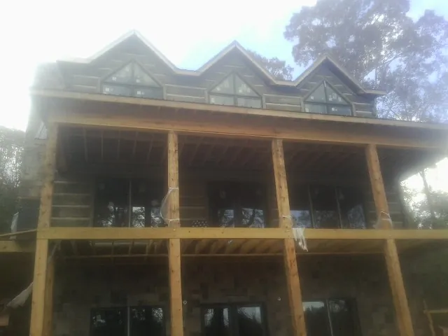 Dormers and porch framing on a large log home under construction — Roof Coating work by our crew in Plain City
