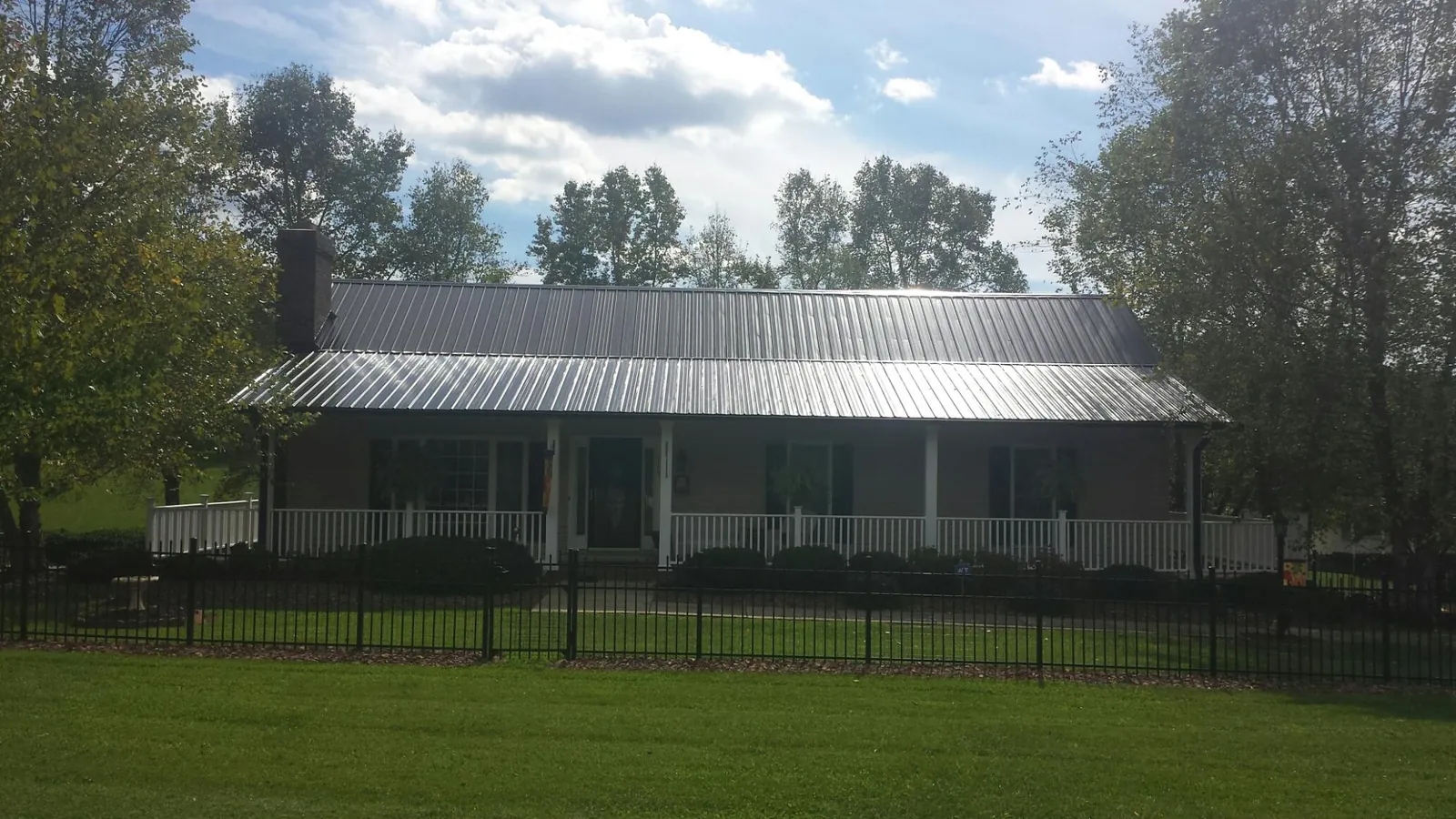 Gray metal roof on a brick ranch with a full width front porch — Gutter Guard Installation work by our crew in Plain City
