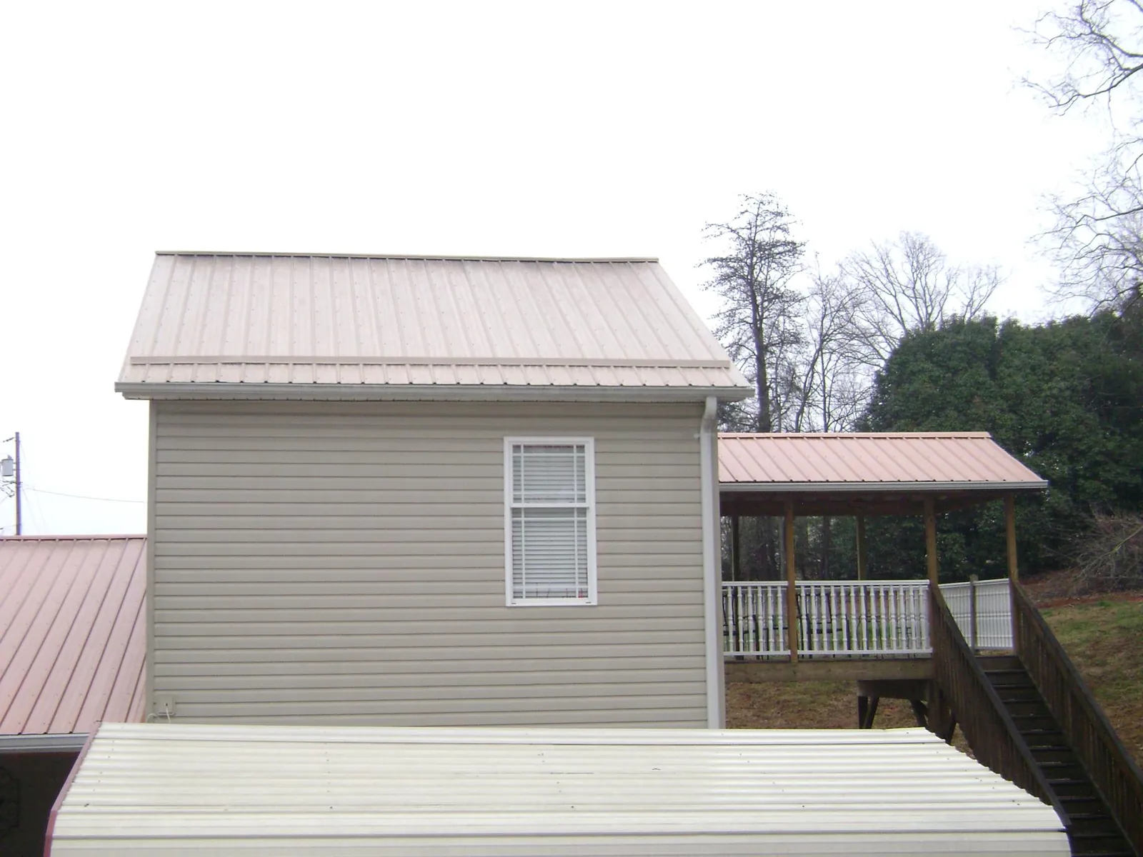 Tan metal roofs on a two story addition and attached porch, from a Roof Replacement job in Plain City