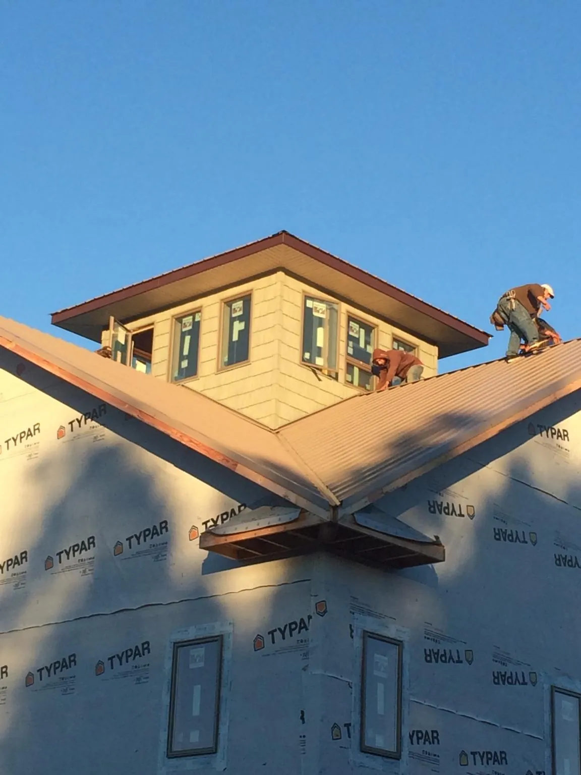 Roofers working around a rooftop cupola on a new metal roof at sunset — Roof Waterproofing in Plain City by Roofing Brothers